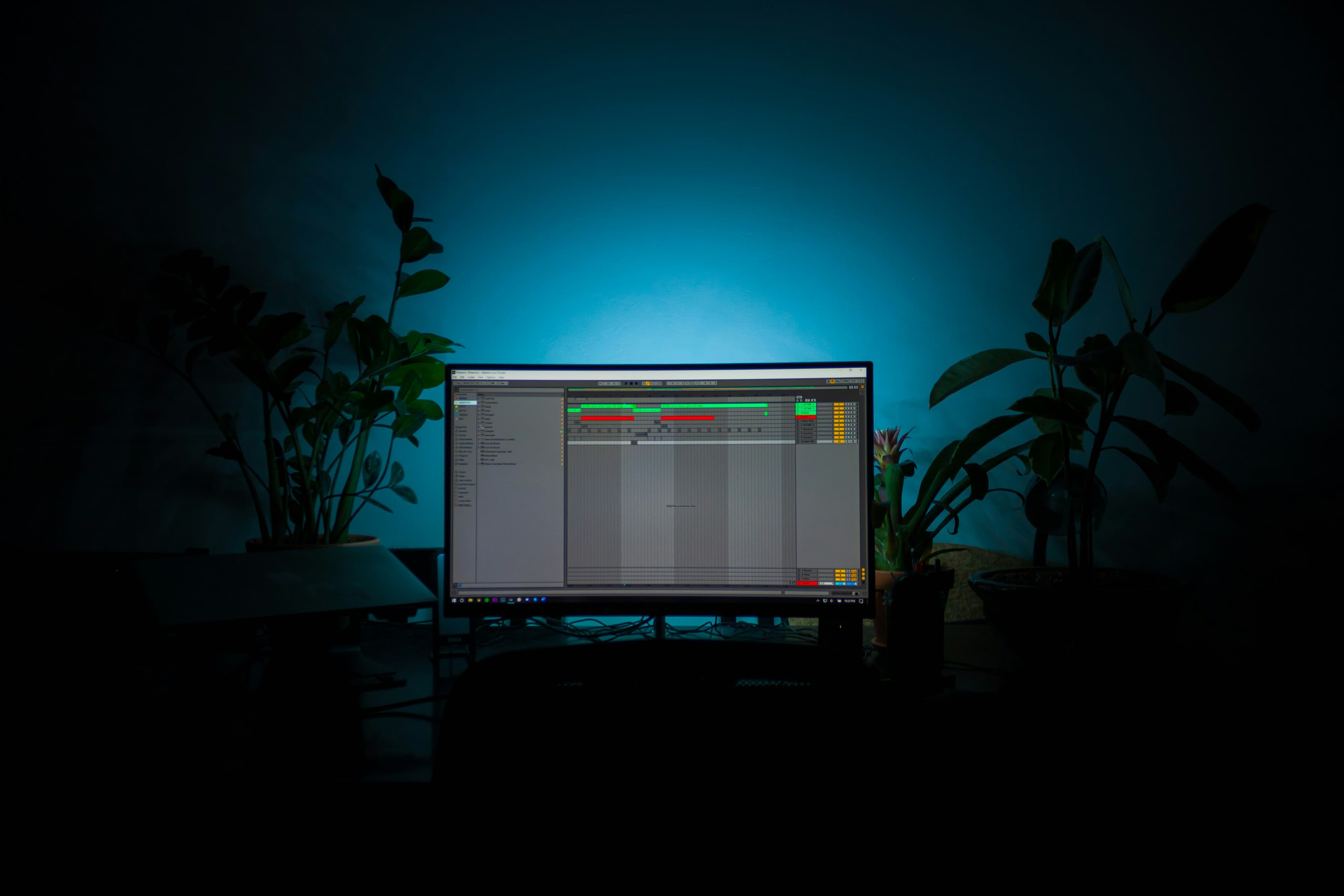 Producers collaborating in a softly lit studio, gathered around a laptop and audio gear.